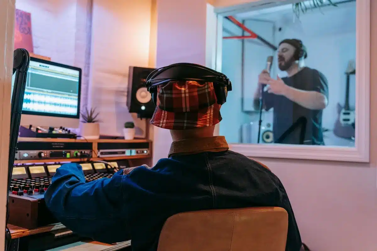 Junge Musikerinnen und Musiker verschiedener Herkunft arbeiten gemeinsam an einer Mischkonsole in einem Tonstudio