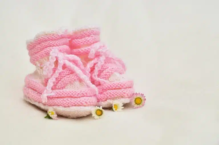 Hände halten ein Geburtsurkunde oder Babybuch mit Stift auf einem Schreibtisch