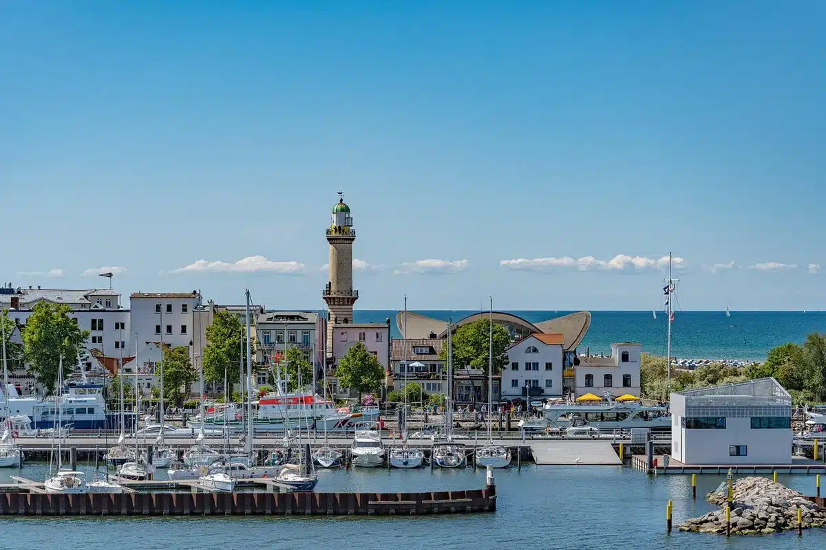 Radfahrerin auf Küstenweg mit Blick auf Ostsee und Backsteingebäude