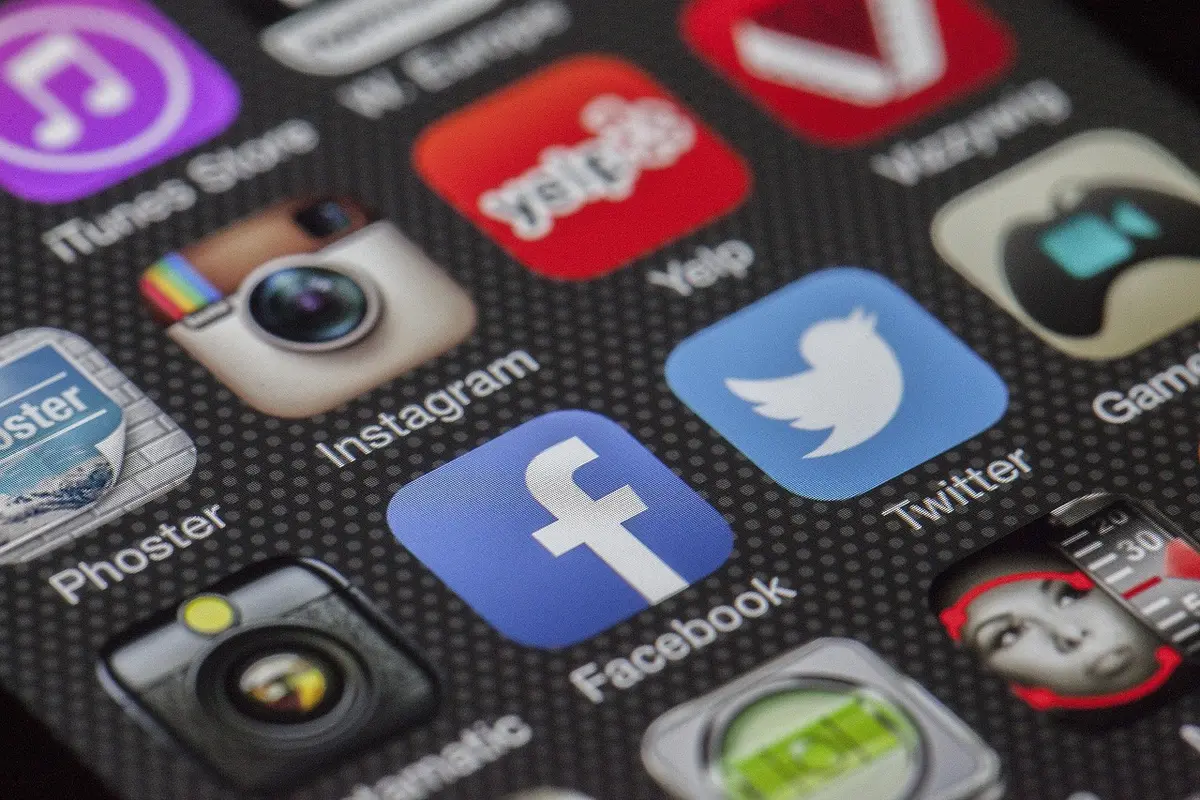 Hand hält Smartphone mit Social-Media-Post, im Hintergrund verschwommen ein Foto