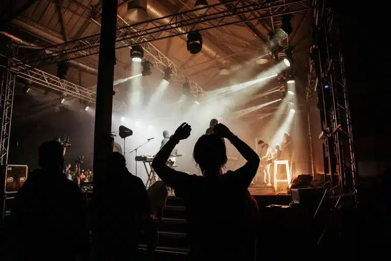 Dunkle Bühne mit Schlagzeug-Silhouette und Gitarrenständern, leere Roadcases