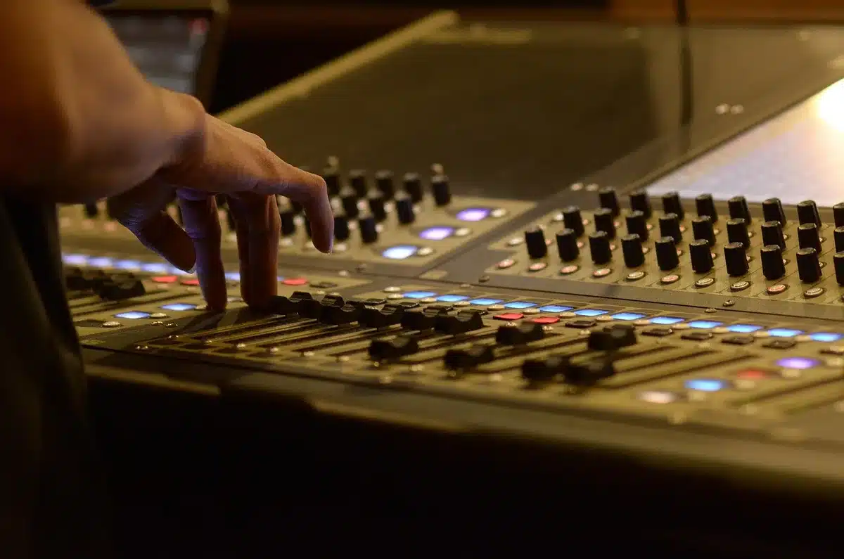 Hände an einem Mixer, Laptop und unbeschriftete Vinylplatten in einem Proberaum