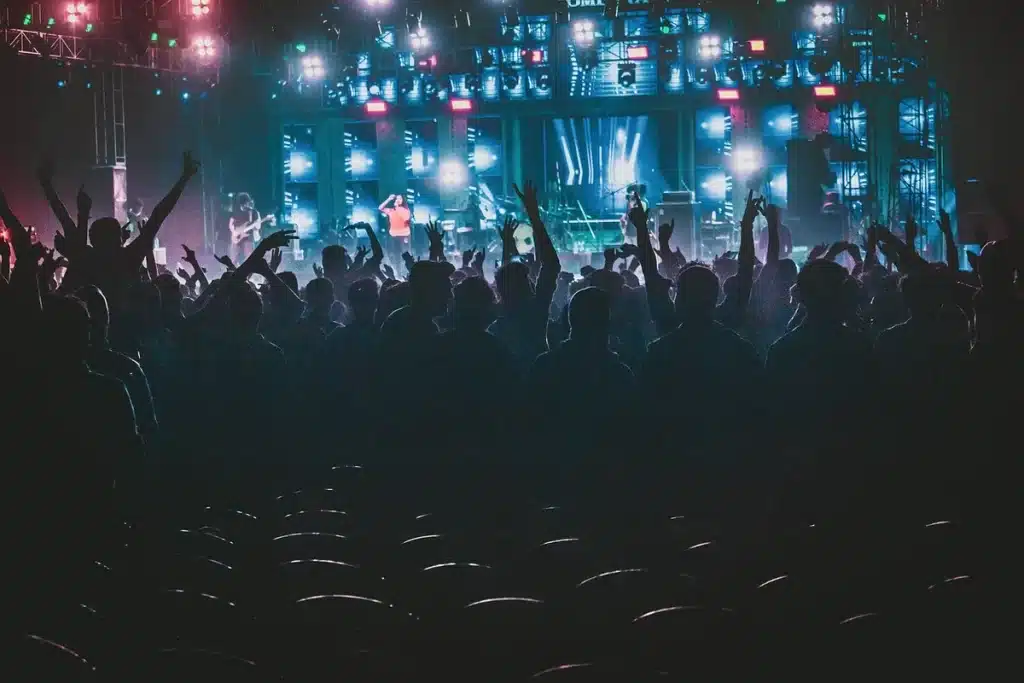 Silhouetten von Konzertbesuchern vor einer modernen Arena bei Abendlicht